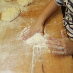 Baguettezubereitung...sie streut Mehl auf die Arbeitsfläche.